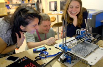 Three students working with a 3D printer in a Fab Lab.
